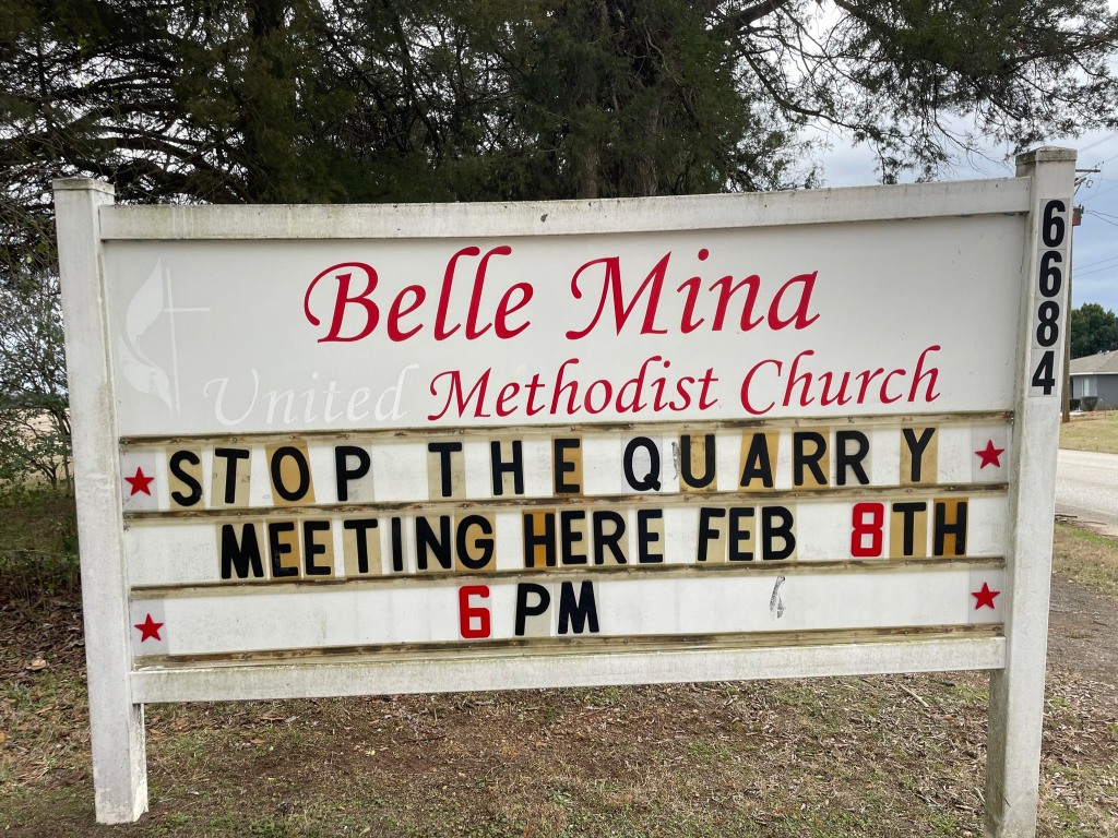 A road sign for the Belle Mina Methodist Church with the following message: "Stop the Quarry Meeting Here Feb 8th 6pm."